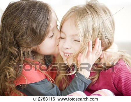 Stock Photograph - Girl kissing sister on cheek. Fotosearch