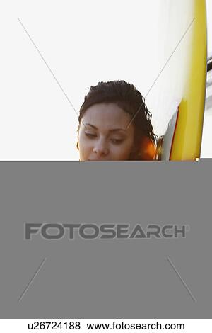 Stock Photo - Girl leaning against surfboard on beach. Fotosearch