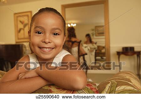 Stock Image - Girl leaning sofa with bride in background. Fotosearch