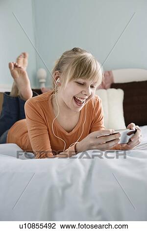 Stock Image - Girl listening to mp3 player. Fotosearch