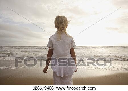Stock Photograph - Girl looking out at ocean. Fotosearch
