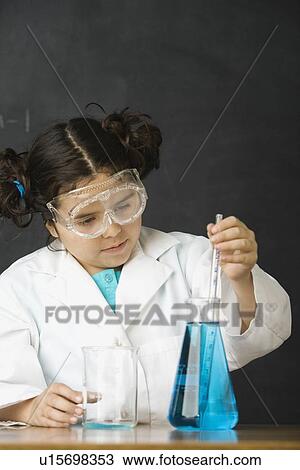 Stock Image - Girl measuring liquid in science class. Fotosearch