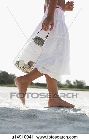Girl on beach carrying jar of shells View Large Photo Image Stock Image - Girl on beach carrying jar of shells. Fotosearch