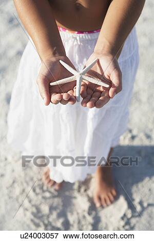 Stock Photo - Girl on beach holding delicate starfish. Fotosearch