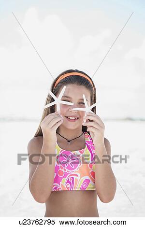 Stock Photography - Girl on beach holding delicate starfish. Fotosearch