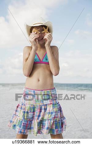 Girl on beach holding starfish View Large Photo Image Stock Image - Girl on beach holding starfish. Fotosearch