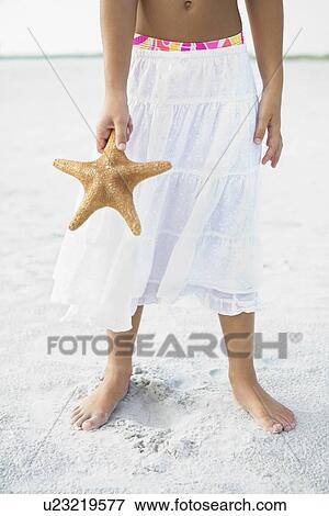 Stock Photo - Girl on beach holding starfish. Fotosearch