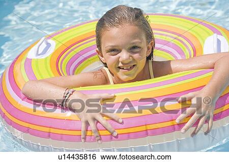 Girl playing in inflatable tube in swimming pool View Large Photo Image Stock Photograph - Girl playing in inflatable tube in swimming pool. Fotosearch