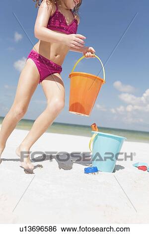 Girl playing with sand buckets on beach View Large Photo Image Stock Photograph - Girl playing with sand buckets on beach. Fotosearch
