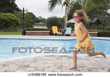 Stock Photo - Girl running beside swimming pool. Fotosearch