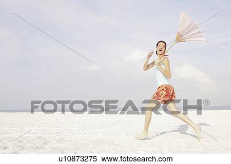 Girl running on beach with umbrella View Large Photo Image Stock Photography - Girl running on beach with umbrella. Fotosearch