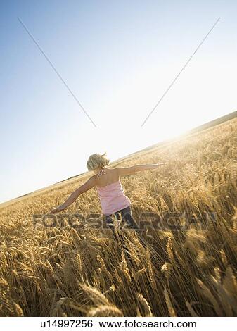 Stock Photograph - Girl running through tall wheat field. Fotosearch