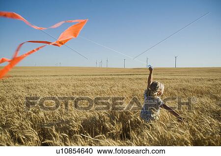 Girl running with kite on wind farm View Large Photo Image Stock Image - Girl running with kite on wind farm. Fotosearch
