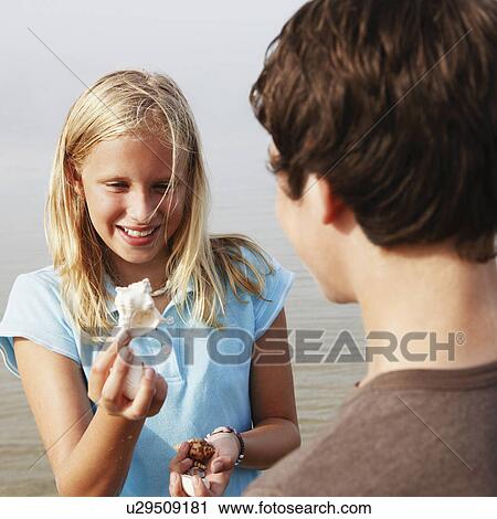 Stock Image - Girl showing shell to friend. Fotosearch