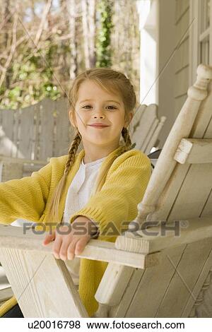 Stock Photo - Girl sitting in chair on porch. Fotosearch