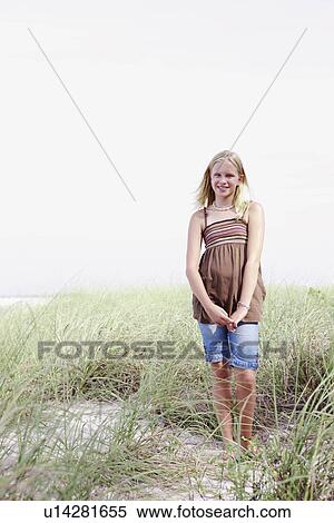 Stock Photography - Girl standing on grassy sand dune. Fotosearch