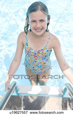 Stock Photo - Girl standing on swimming pool ladder. Fotosearch