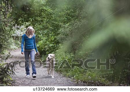 Stock Photo - Girl walking dog on forest path. Fotosearch