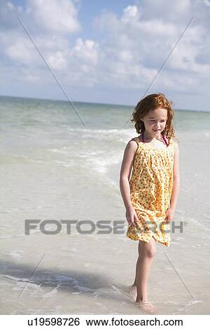 Stock Photograph - Girl walking through ocean surf. Fotosearch