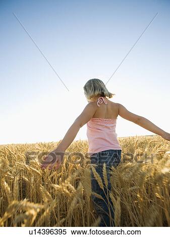 Stock Photography - Girl walking through tall wheat field. Fotosearch