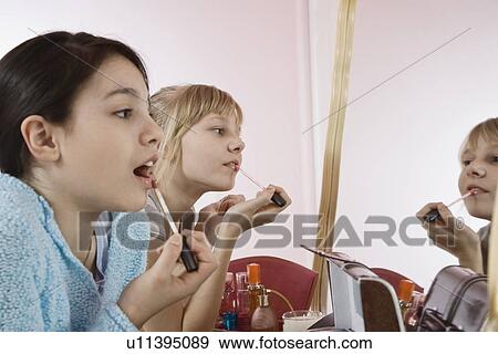 Girls applying lip gloss View Large Photo Image Stock Photo - Girls applying lip gloss. Fotosearch
