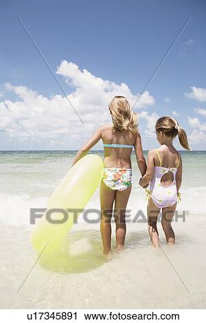 Girls carrying inflatable ring into ocean View Large Photo Image Stock Image - Girls carrying inflatable ring into ocean. Fotosearch