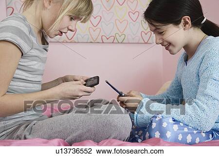 Stock Image - Girls dialing cell phones. Fotosearch
