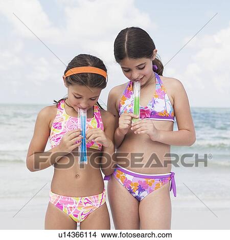 Girls eating ice pops on beach View Large Photo Image Picture - Girls eating ice pops on beach. Fotosearch