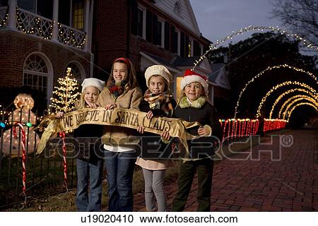 Stock Image - Girls holding Santa Claus banner. Fotosearch