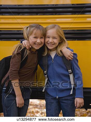 Girls hugging in front of school bus View Large Photo Image Stock Photo - Girls hugging in front of school bus. Fotosearch