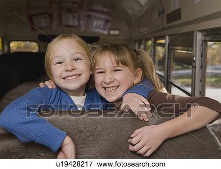 Stock Photo - Girls hugging on school bus. Fotosearch