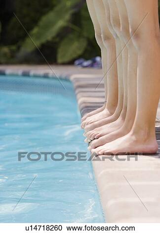 Stock Image - Girls in a row at edge of swimming pool. Fotosearch