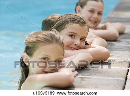 Stock Photo - Girls in a row leaning on edge of swimming pool. Fotosearch