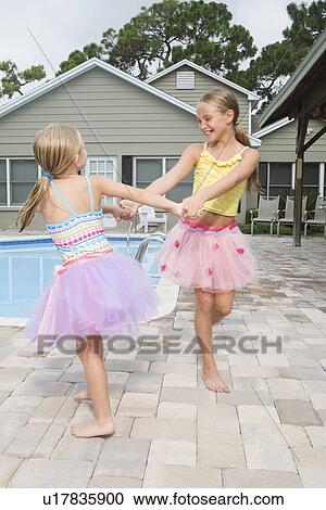 Stock Image - Girls in tutus playing by swimming pool. Fotosearch