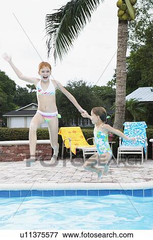 Stock Photo - Girls jumping into swimming pool. Fotosearch