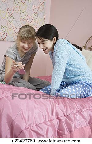 Stock Photo - Girls looking at cell phone. Fotosearch