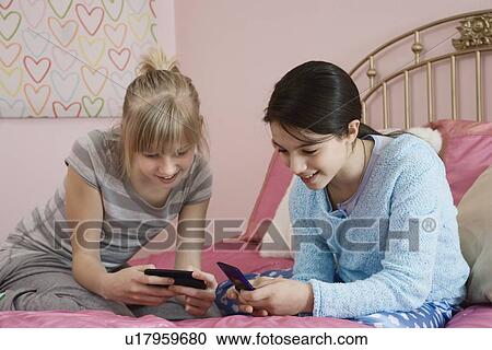 Stock Image - Girls looking at cell phones. Fotosearch