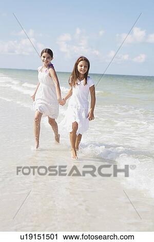Stock Image - Girls running in ocean. Fotosearch