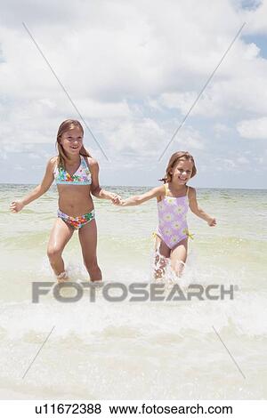 Stock Photo - Girls running in ocean. Fotosearch