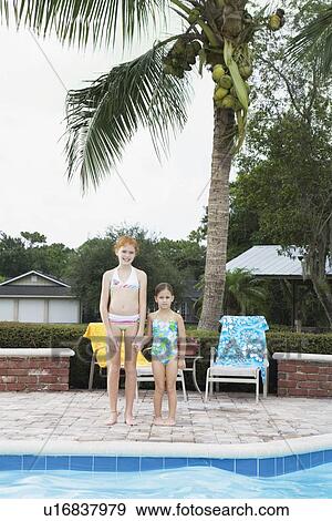 Stock Photo - Girls standing at edge of swimming pool. Fotosearch