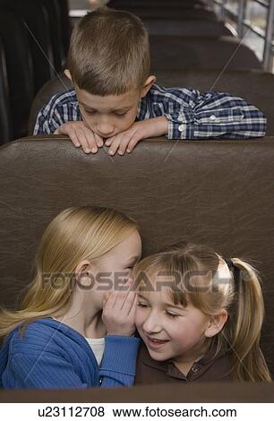 Stock Photo - Girls telling secret on school bus. Fotosearch
