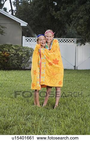 Stock Image - Girls wrapped in towels on lawn. Fotosearch