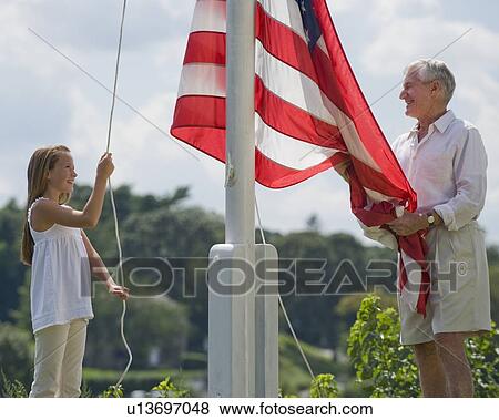 Grandfather and granddaughter raising American flag View Large Photo Image Stock Photo - Grandfather and granddaughter raising American flag. Fotosearch