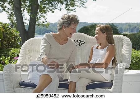 Stock Image - Grandmother and granddaughter sitting on porch. Fotosearch