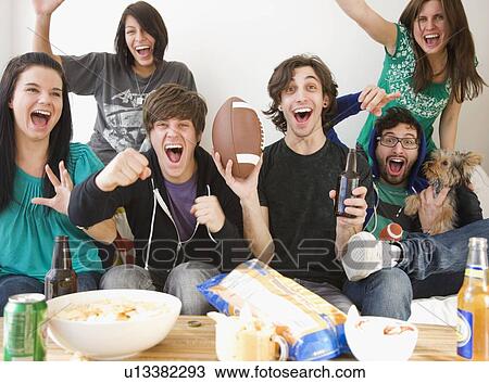 Group of friends cheering on sofa View Large Photo Image Stock Image - Group of friends cheering on sofa. Fotosearch