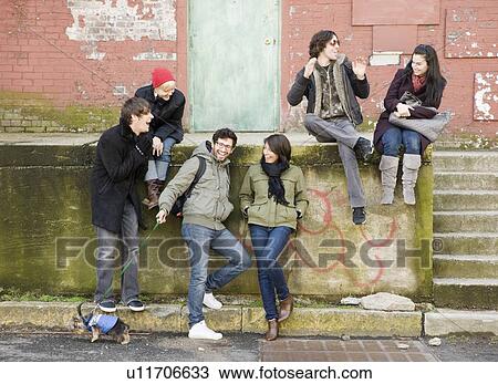 Stock Image - Group of friends sitting in urban scene. Fotosearch