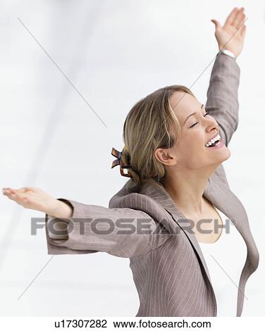 Stock Image - Happy businesswoman celebrating with arms outstretched. Fotosearch