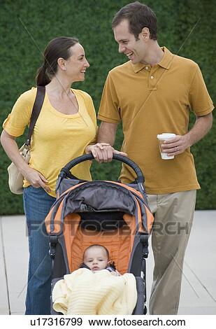 Happy couple walking baby in stroller View Large Photo Image Stock Photo - Happy couple walking baby in stroller. Fotosearch