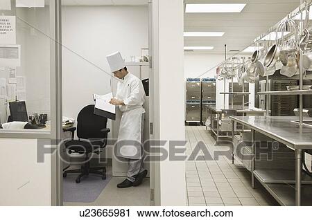Stock Image - Head chef standing in kitchen office. Fotosearch