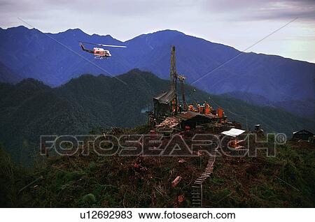 Stock Image - Helicopter flying over oil drilling platform in Indonesia. Fotosearch